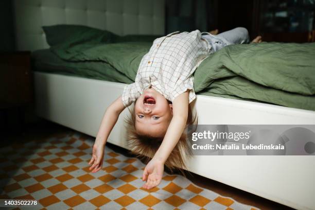 european toddler child hanging from bed upside down - intérieur deco prendre la pose joie photos et images de collection