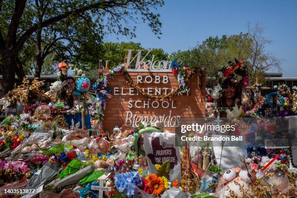 The Robb Elementary School sign is seen covered in flowers and gifts on June 17, 2022 in Uvalde, Texas. Committees have begun inviting testimony from...