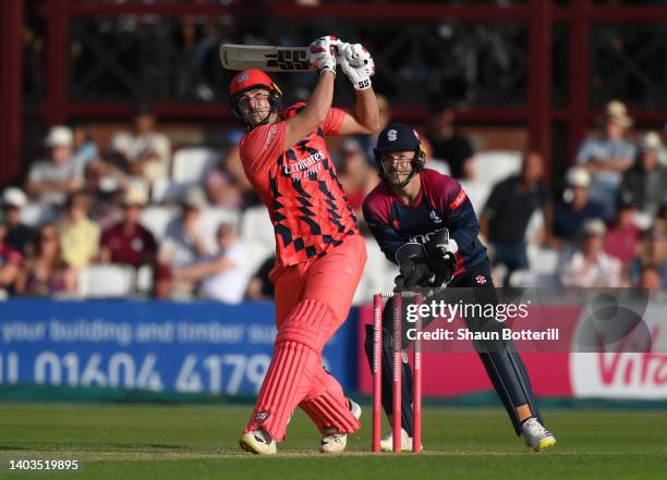 Tim David of Lancashire Lightning plays a shot as Northamptonshire Steelbacks wicket keeper Lewis McManus looks on during the Vitality T20 Blast...