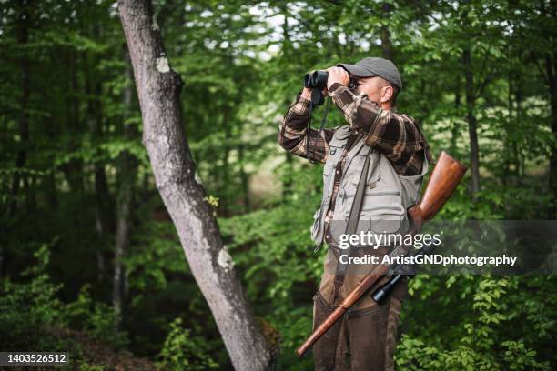 hunter looking through his binoculars. - jager stockfoto's en -beelden