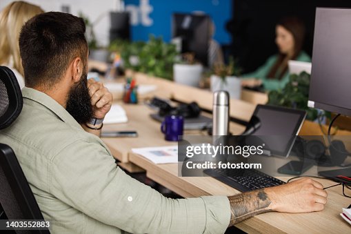 Computer programmer sitting at his desk, contemplating while coding Computer programmer sitting at his desk, contemplating while coding
