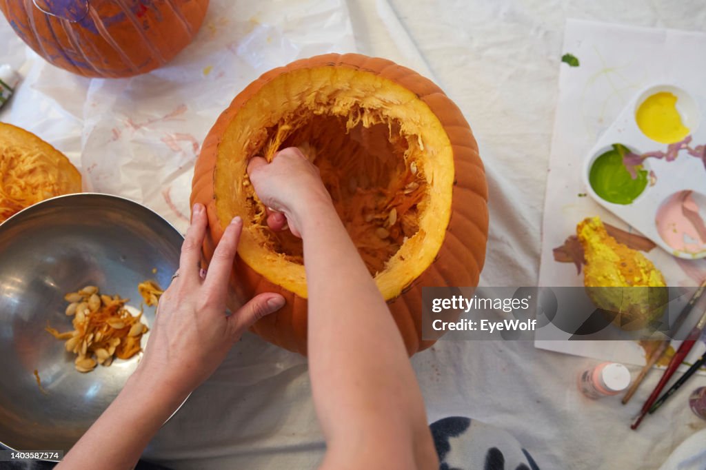 Woman decorating a Jack-O-Lantern pumpkin, taking seeds out of the inside of the pumpkin
