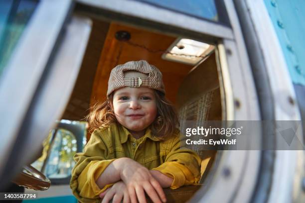 Joyful toddler peeking out the window of an retro tour bus