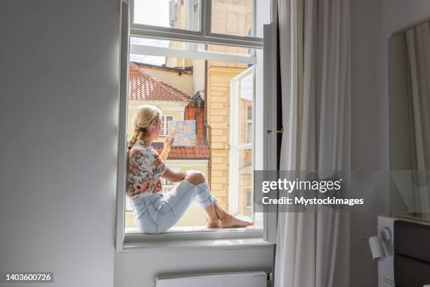 junge frau im hotelzimmer mit blick auf den stadtplan - lüften stock-fotos und bilder