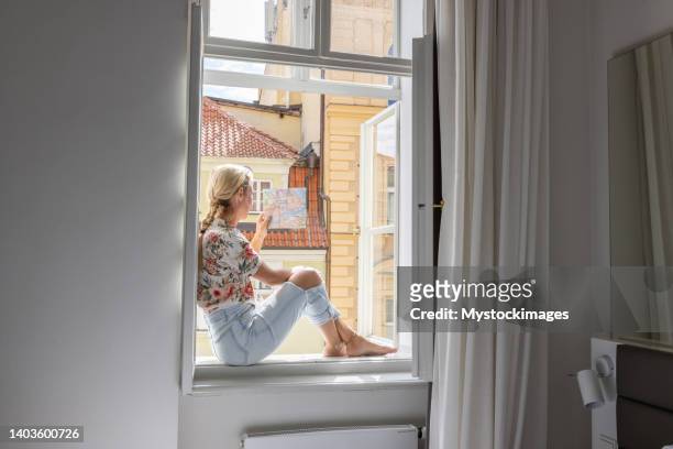 young woman in hotel room looking at city map - paris street woman stockfoto's en -beelden