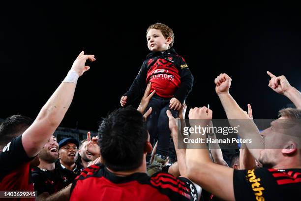 The son of Pablo Matera of the Crusaders is held aloft by Crusaders players celebrating after winning the 2022 Super Rugby Pacific Final match...
