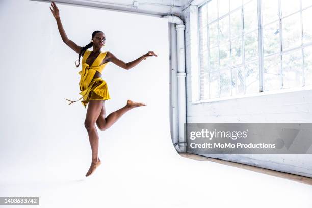 studio portrait of fashionable female professional dancer - fashion woman jumping stock-fotos und bilder