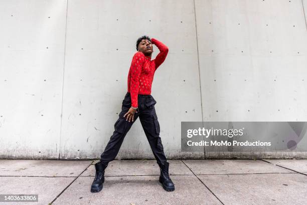 fashionable male professional dancer on urban sidewalk, full length - african male red shirt stock-fotos und bilder