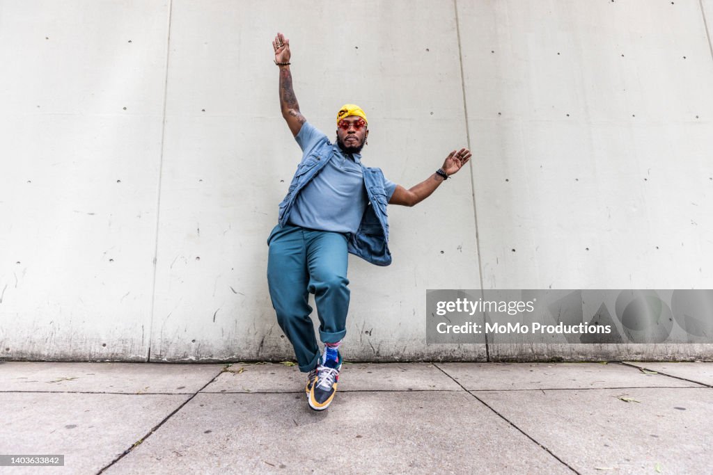 Fashionable male professional dancer on urban sidewalk, full length