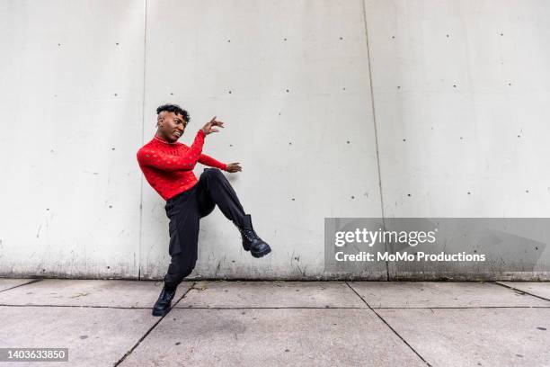 fashionable male professional dancer on urban sidewalk, full length - african male red shirt stock-fotos und bilder