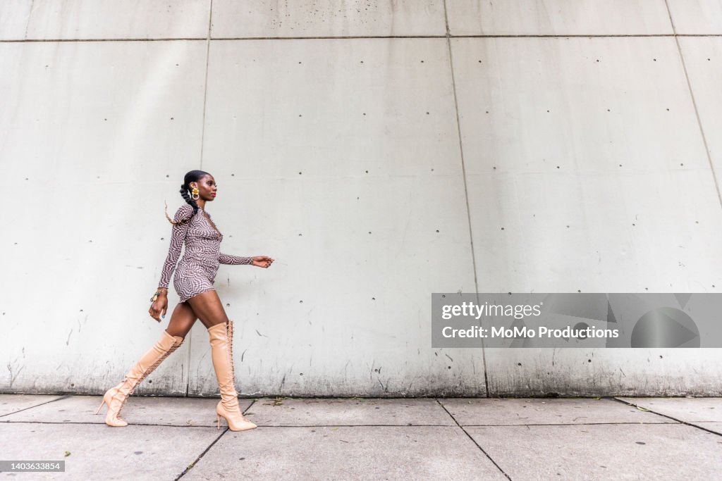 Fashionable female professional dancer on urban sidewalk, full length