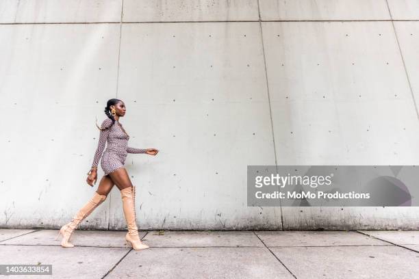fashionable female professional dancer on urban sidewalk, full length - graues kleid stock-fotos und bilder