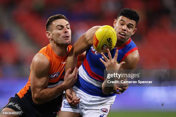 Jason Johannisen of the Bulldogs is tackled by Stephen Coniglio of the Giants during the round 14 AFL match between the Greater Western Sydney Giants...