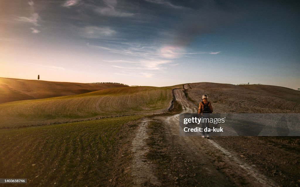 Walking in fields of Val d'Orcia at sunset. Italy, Tuscany
