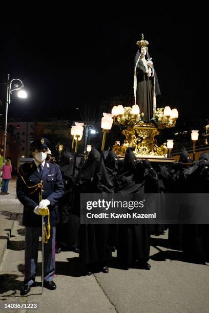 An Italian guard of honor wearing a COVID-19 protective facial mask walks along with hooded men dressed in black robes carrying the statuette of the...