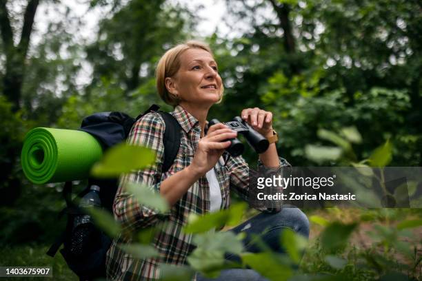 female hiker watching birds through binoculars - fågelskådning bildbanksfoton och bilder