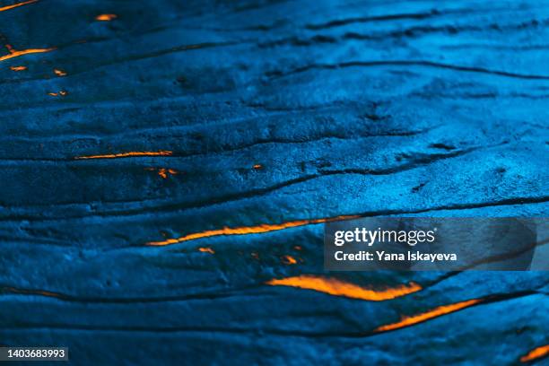 textured metallic colored lava field with hot burning magma - lavastroom stockfoto's en -beelden