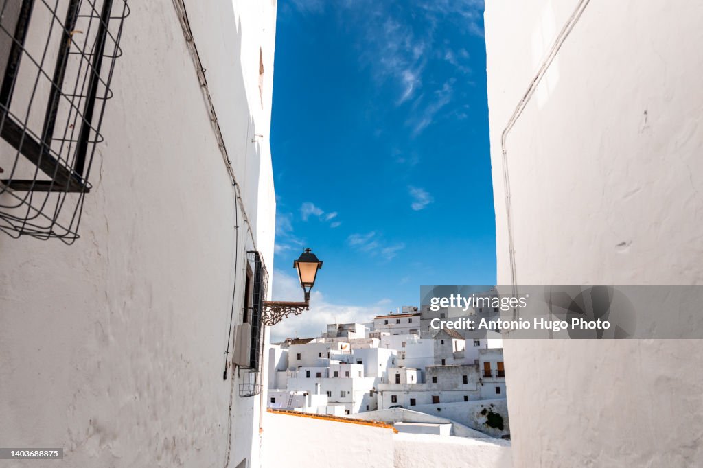 Street and set of white houses against blue sky in Vejer de la Frontera, Cadiz, Spain.