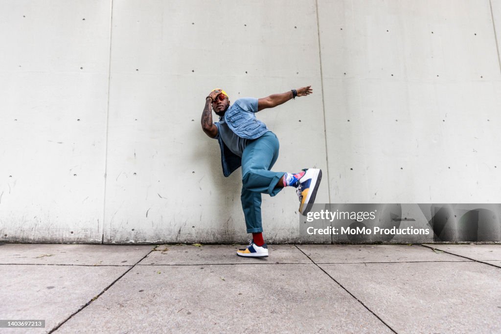 Fashionable male professional dancer on urban sidewalk, full length