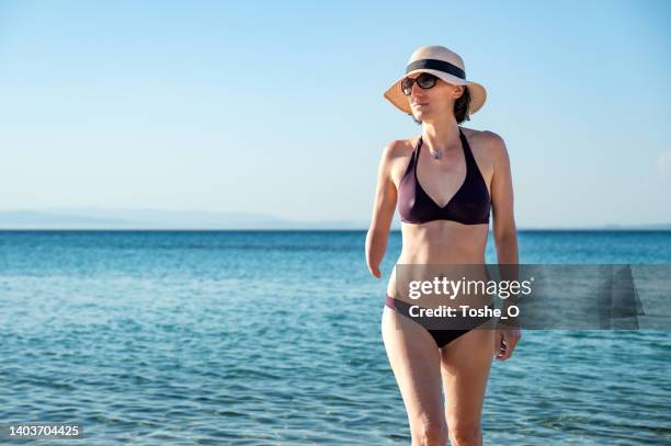 hermosa joven con discapacidad disfruta del verano en la playa - disabled sign fotografías e imágenes de stock