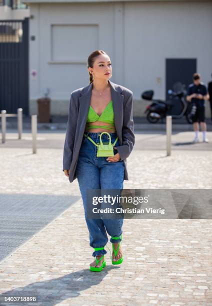 Guest is seen wearing green Jacquemus bag, green top, grey blazer, denim jeans, laced sandals outside MSGM during Milan Fashion Week S/S 2023 on June...