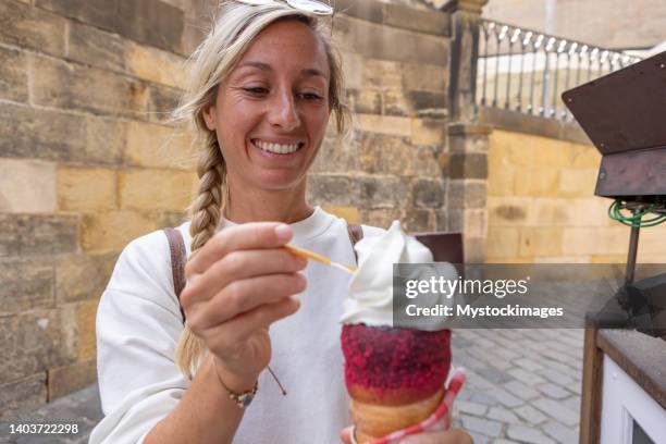 young woman eating traditional ice cream in prague, street food - trdelník stock pictures, royalty-free photos & images