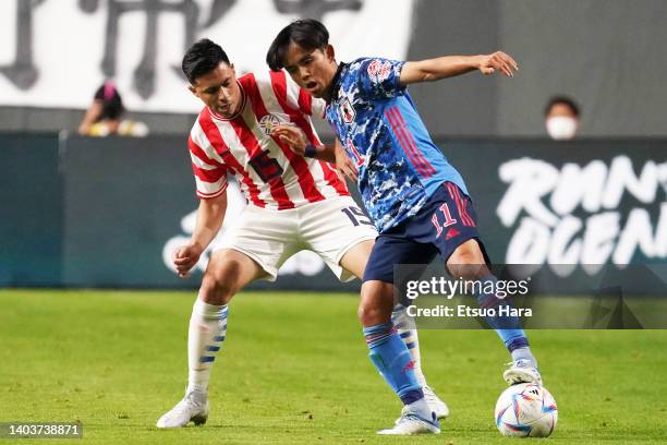 Takefusa Kubo of Japan in action under pressure from Blas Riveros of Paraguay during the international friendly match between Japan and Paraguay at...