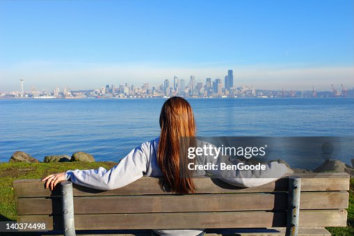 Woman sitting in wooden bench watching the city view Woman sitting in wooden bench watching the city view