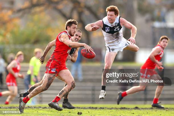 Liam Mackie of the Bullants kicks the ball under pressure from Jesse Joyce of the Sharks during the round 13 VFL match between the Northern Bullants...