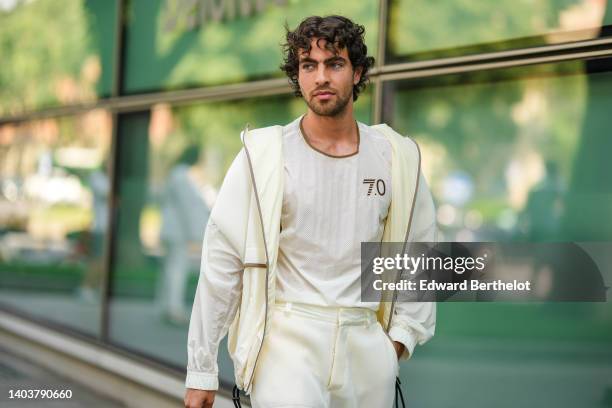 Yanis Serbout wears silver earrings, a white latte cut-out pattern t-shirt from Emporio Armani, a white latte / pale yellow cut-out pattern zipper...