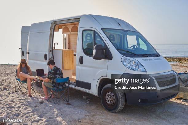 young couple on vacation in a camper van on the beach - トレーラハウス ストックフォトと画像