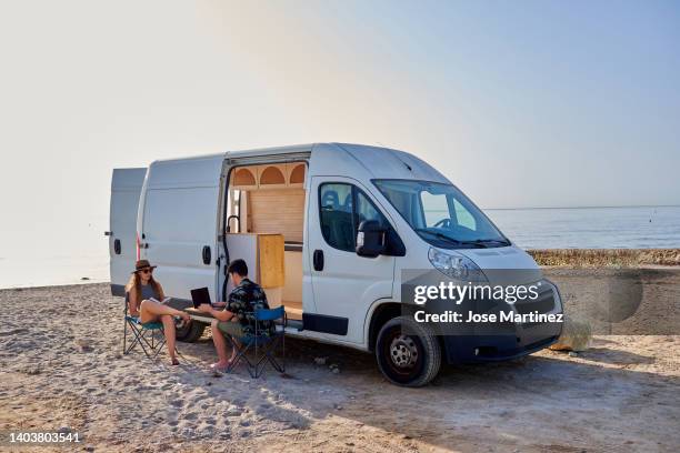 young couple on vacation in a camper van on the beach - trailer home stock pictures, royalty-free photos & images