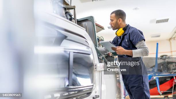 serious african american mechanic standing near jet and fixing engine, side view - vliegtuigmonteur stockfoto's en -beelden