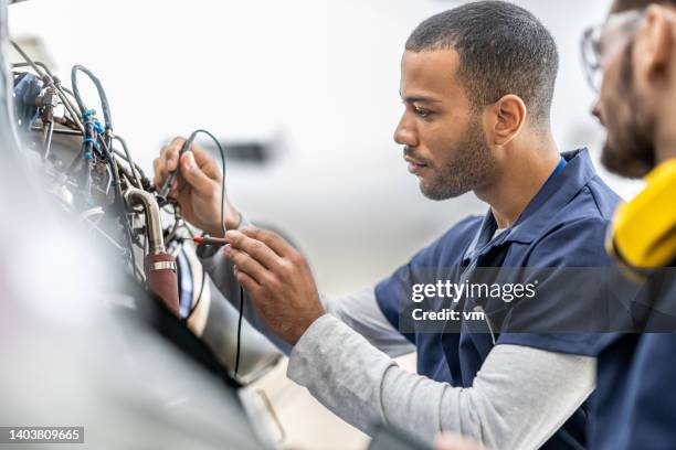 aircraft engineers examining helicopter engine with multimeter, close up - engineering imagens e fotografias de stock