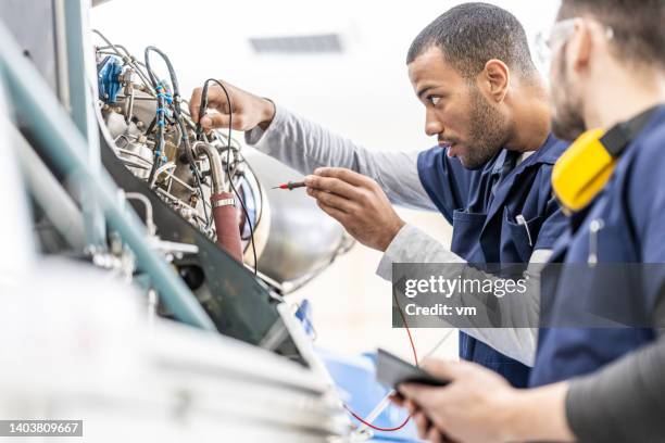 aircraft mechanics examining helicopter engine with multimeter, using multimeter, side view - aerospace industry imagens e fotografias de stock