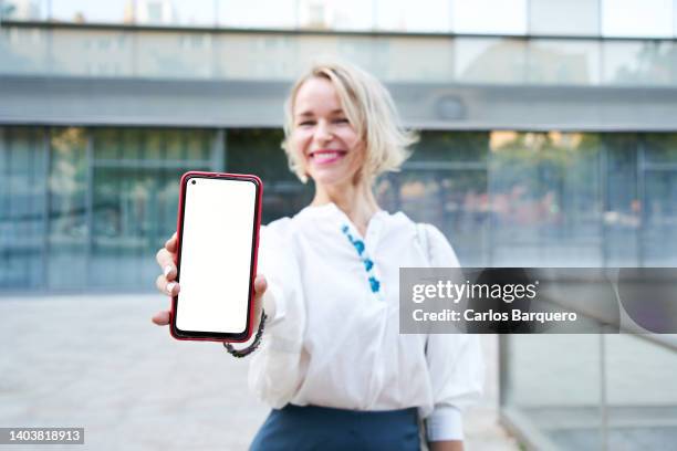 beautiful middle age blond woman showing her  phone. - hand showing stockfoto's en -beelden