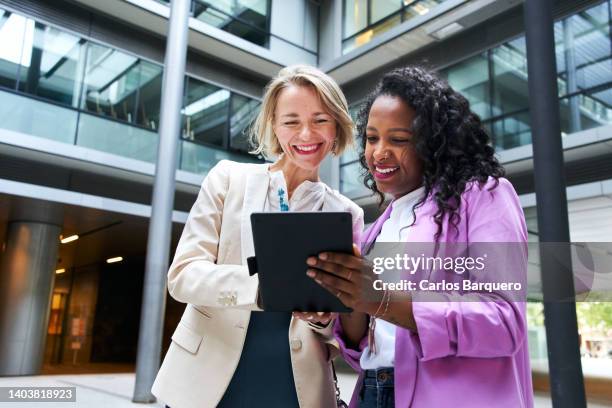 two business women looking at a tablet computer, discussing about a business topic. - team bonding stock pictures, royalty-free photos & images