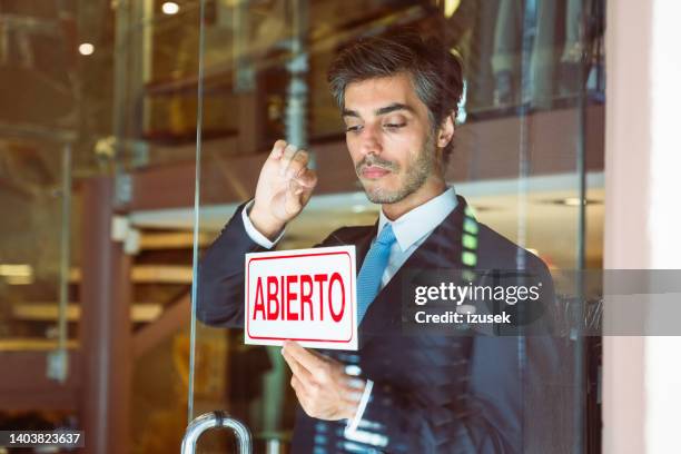 male owner putting open sign on entrance door - store closing stock pictures, royalty-free photos & images