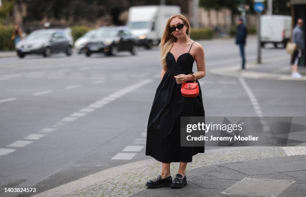 Sonia Lyson seen wearing a black Miu Miu sunglasses, a black long maxi dress from Zara, a red leather mini Gucci Bamboo bag and black leather loafers...