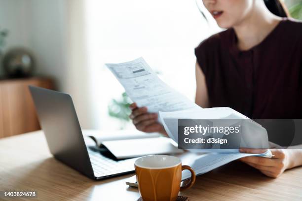 cropped shot of asian woman sitting at dining table, handling personal finance with laptop. she is making financial plan and planning budget as she go through her financial bills, tax and expenses at home. wealth management, banking and finance concept - budget ストックフォトと画像