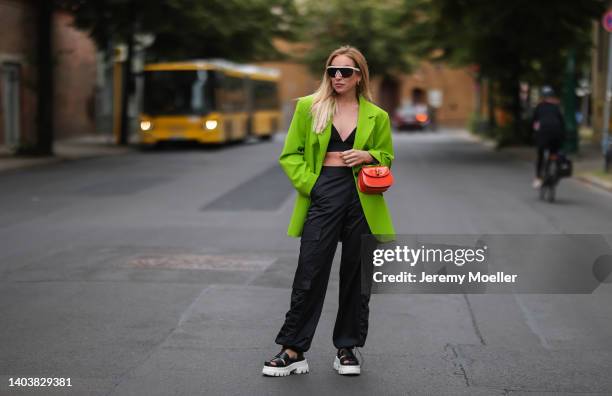 Sonia Lyson seen wearing a white Bottega Veneta sunglasses, a black bra top from Trendyol, a yellow green/acid green oversize blazer from Zara, a...