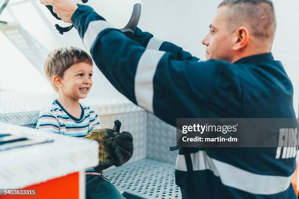 firefighter looking after his son while being on work - child fireman stock pictures, royalty-free photos & images