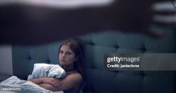 woman in bed looking at a raised arm - home violence stock pictures, royalty-free photos & images