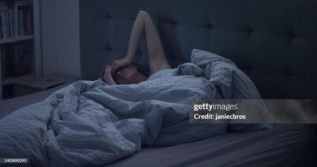 Frau im Bett kann aufgrund von Schlaflosigkeit nicht schlafen