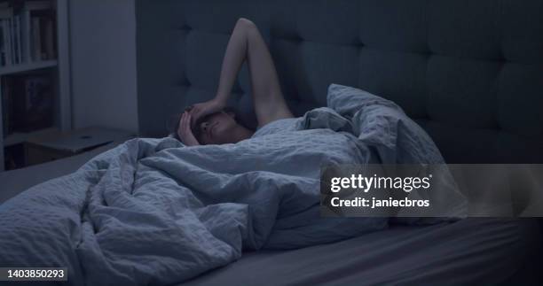 woman in bed can't sleep due to insomnia - negative emotion stockfoto's en -beelden