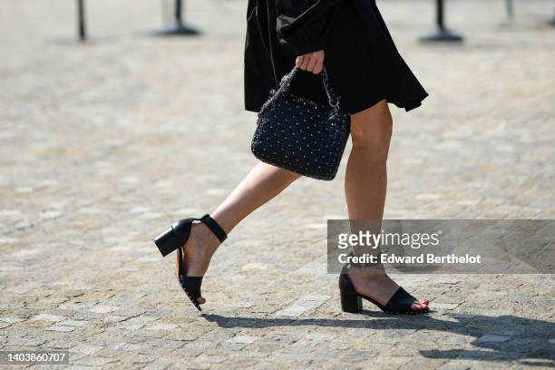 Guest wears a black short dress, a black shirt as a jacket, black shiny leather block heels sandals, a black shiny leather with silver nailed /...