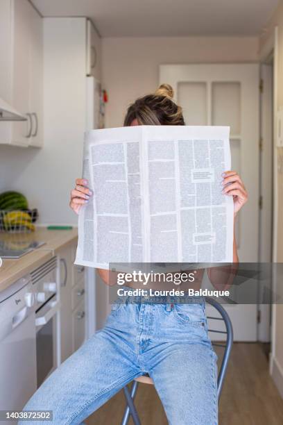 woman holding a newspaper covering her face, sitting - hid face stock pictures, royalty-free photos & images