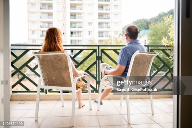 couple sitting together on their hotel patio and looking at the view - back porch stockfoto's en -beelden