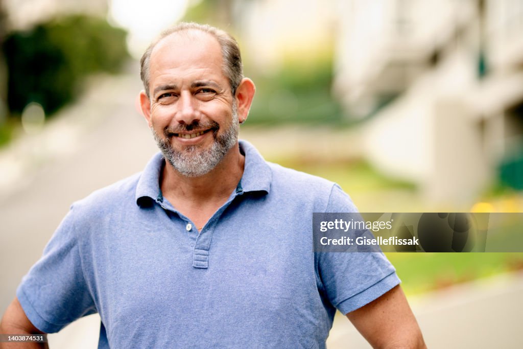 Mature man smiling while standing outside in the summertime