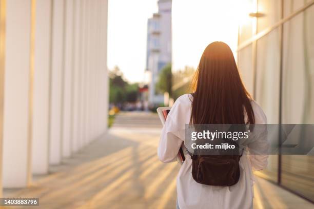 studentessa che cammina vicino all'edificio universitario - studentessa di scuola secondaria foto e immagini stock